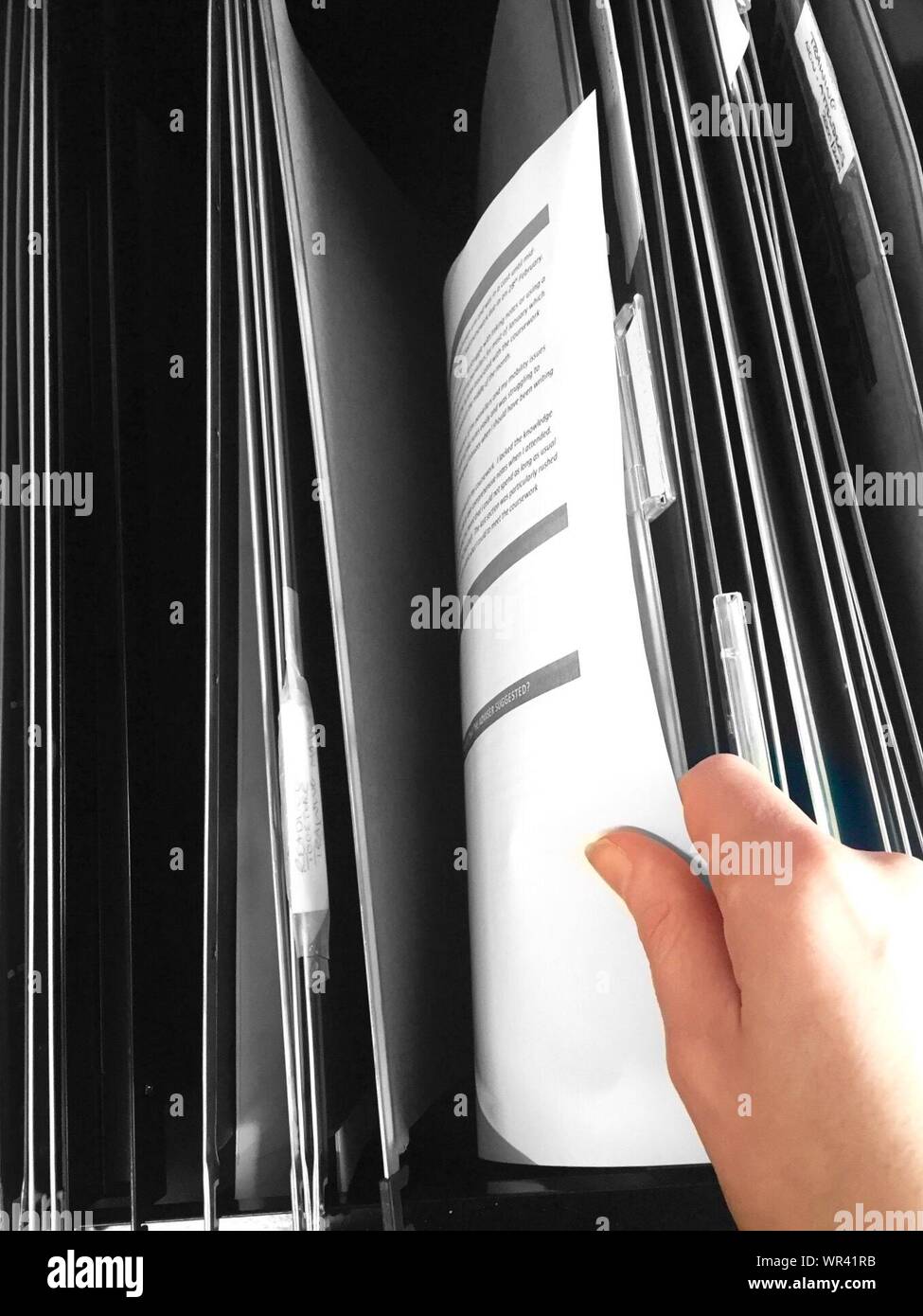 Cropped Image Of Hand Holding Documents In Filing Cabinet At Office Stock Photo