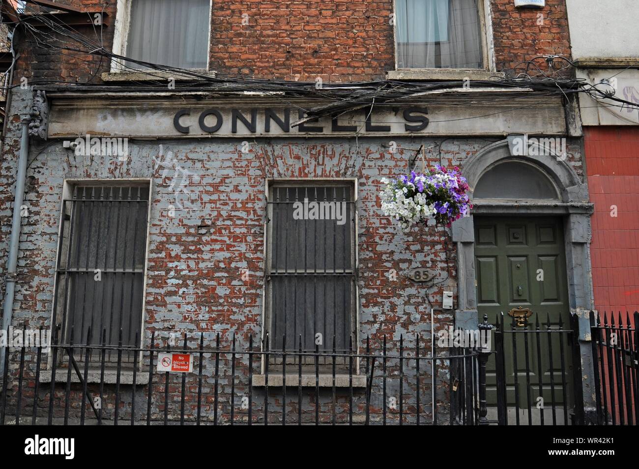 A run down and neglected building with a large hanging basket of