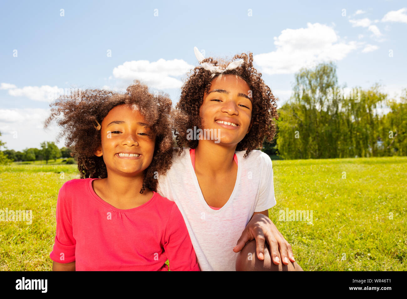 Two happy smiling girls in park lawn portrait Stock Photo - Alamy
