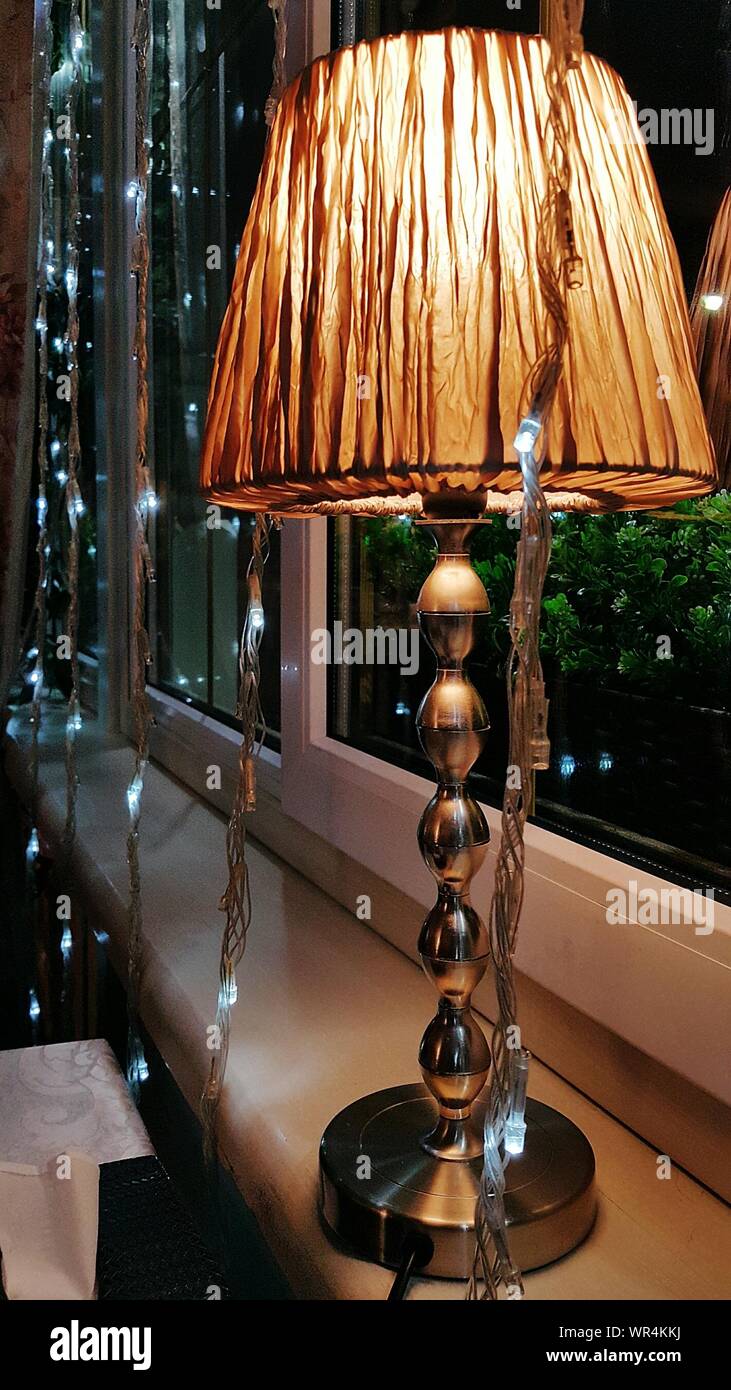 close-up-of-illuminated-lamp-on-window-sill-at-home-WR4KKJ.jpg