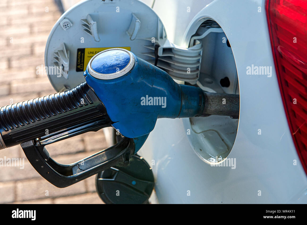 A gun for filling gasoline is inserted into the gas tank of the car. Holding fuel nozzle to refuel gasoline for car Stock Photo