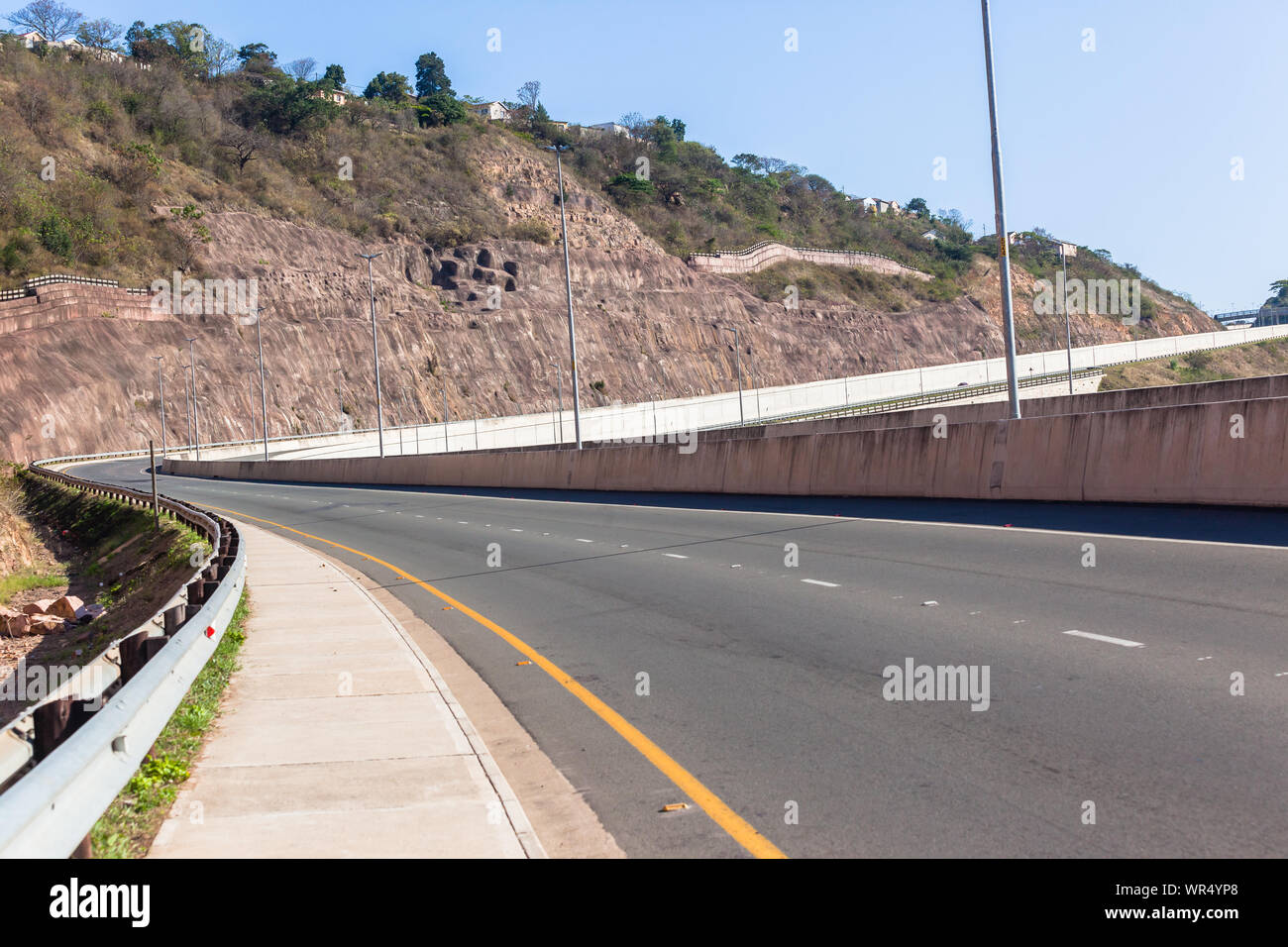 New road highway with concrete walls and pool lanes winding up down through rural valley