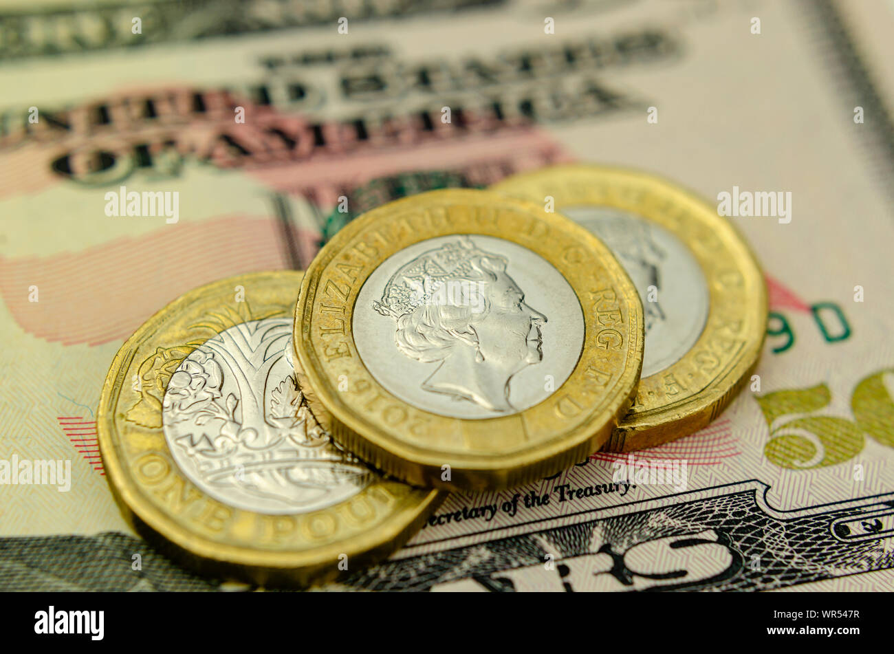 Pile of one pound coins on top of 50 dollar note. Close up photo, with shallow depth of field. Concept for currency exchange, business and finance. Stock Photo