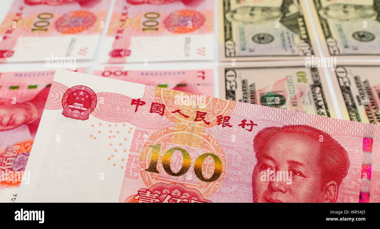 Chinese 100 Yuan bill close up image with flat laying US dollars and other Yuan notes on the background. Stock Photo