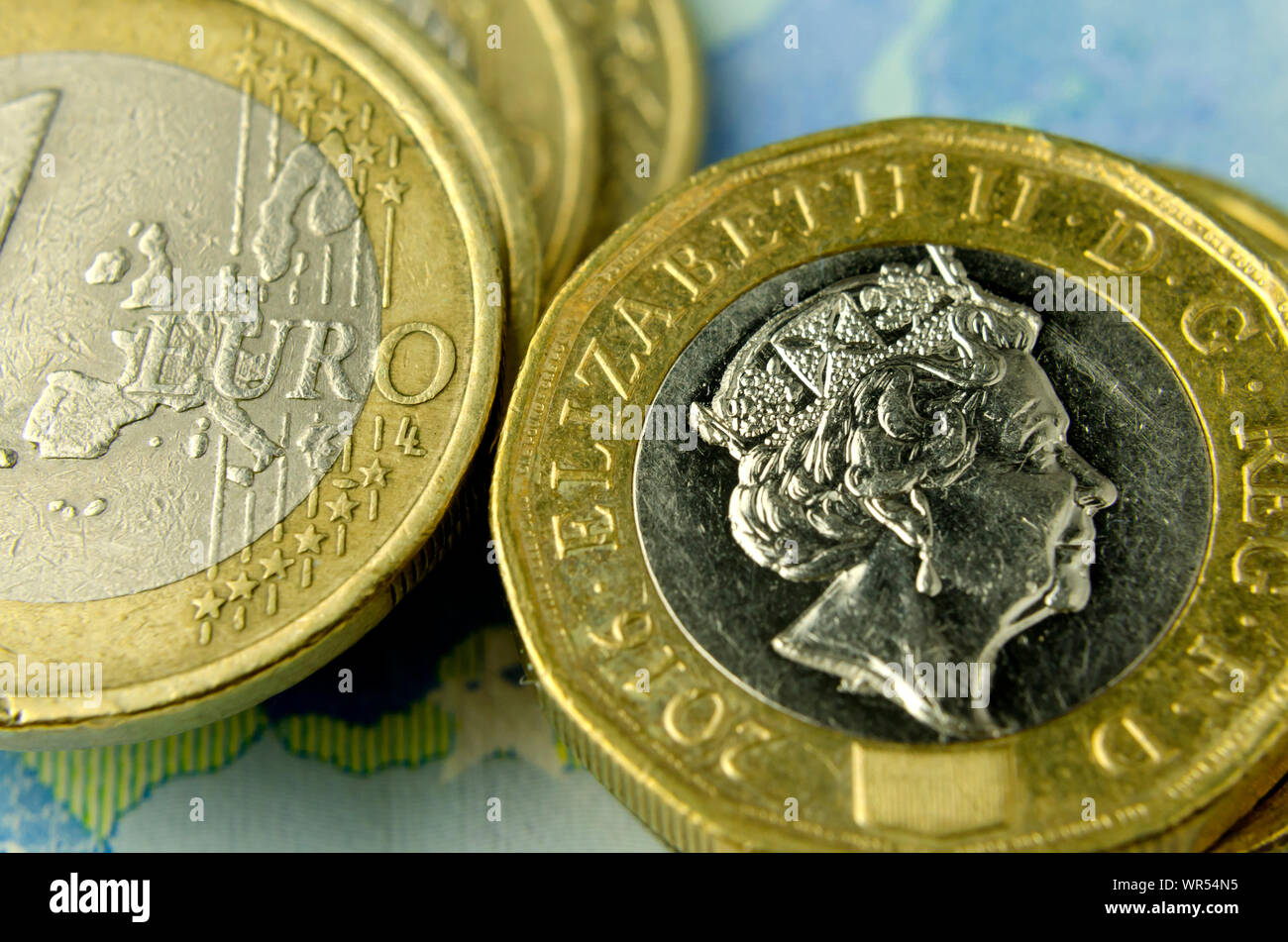 Stack of british pound coins next to one euro coins where visible only the EU map. Illustrates that the UK leaving the EU. Stock Photo