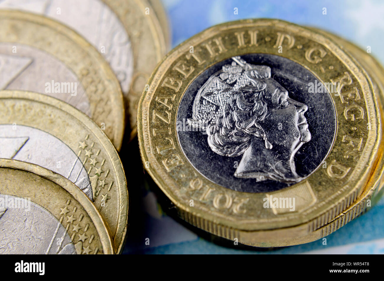 Stack of British pound coins next to the fallen stack of euro coins. Macro photo. Stock Photo