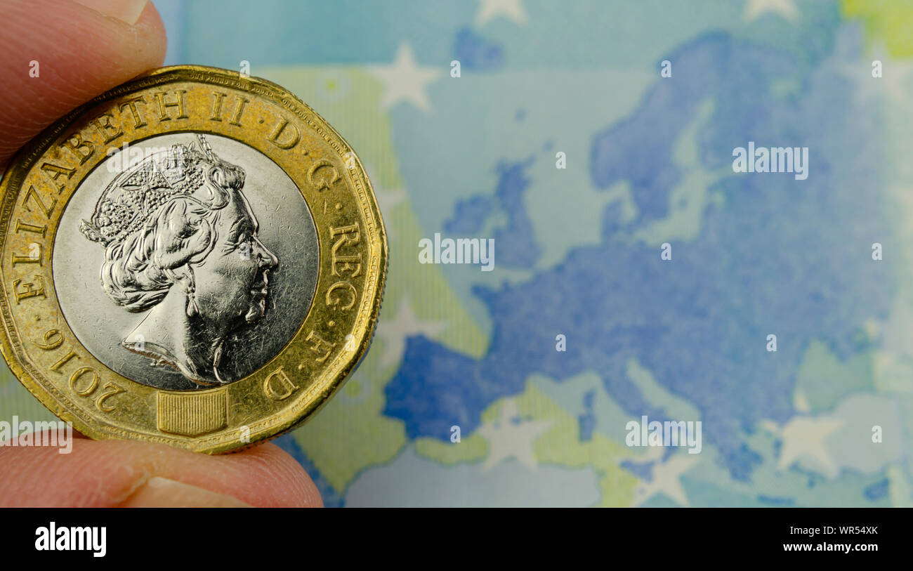 One pound coin hold in hand above the 20 Euros banknote, next to the map of the EU. Concept for currency exchange, banking and BREXIT. Stock Photo