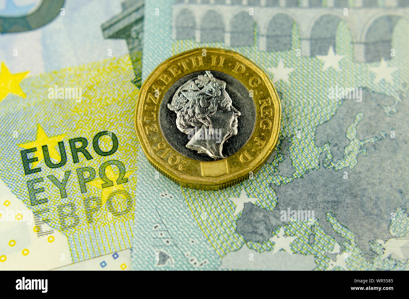 One pound coin on top of 5 Euros banknote, next to the map of the EU and words EURO. Flat lay view. Concept for currency exchange, finance or UK - EU Stock Photo
