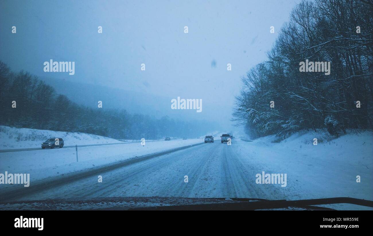 Cars On Snow Covered Street Seen Through Windshield Stock Photo
