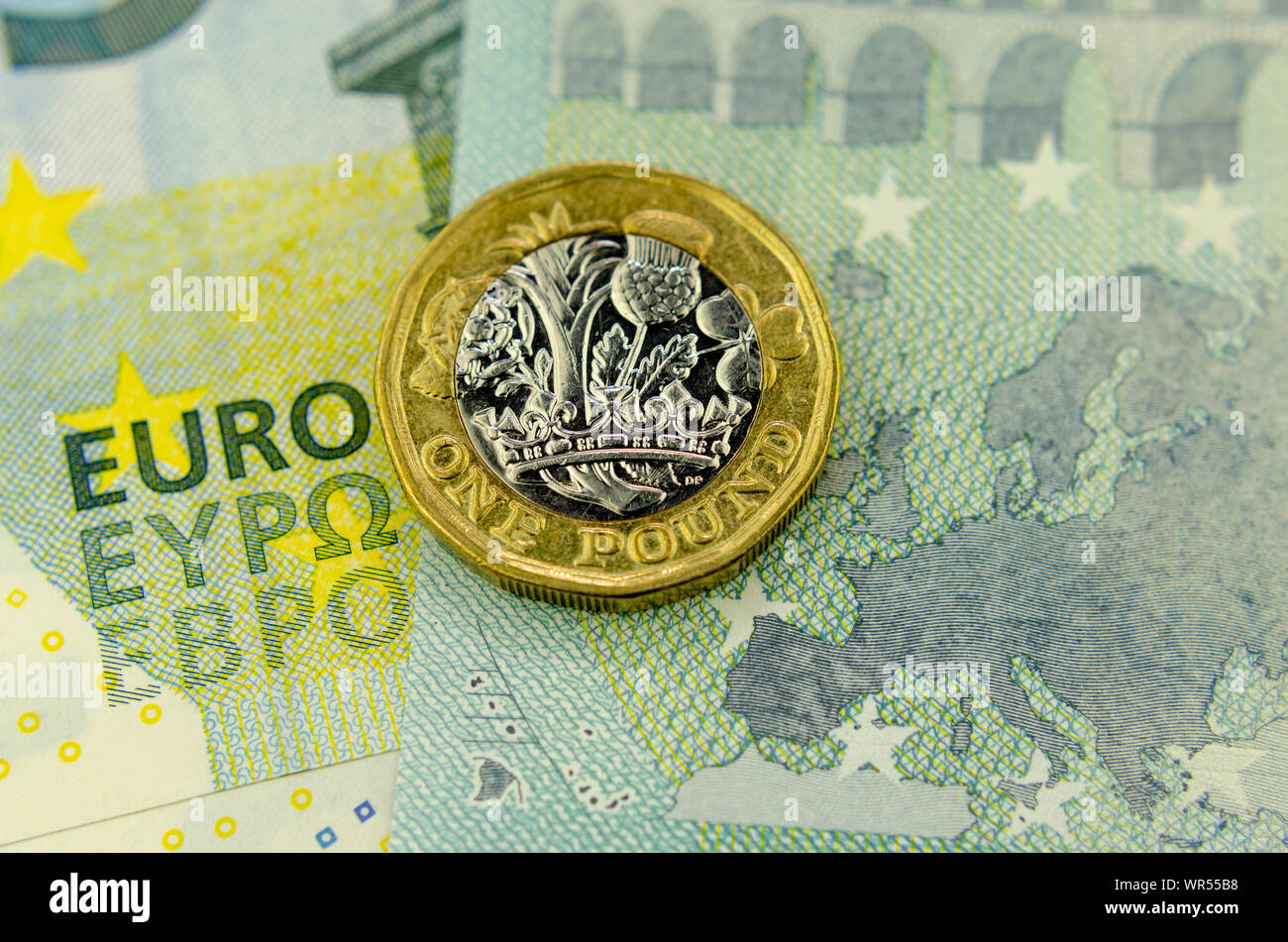 One pound coin on top of 5 Euros banknote, next to the map of the EU and words EURO. Flat lay view. Concept for currency exchange, finance or UK - EU Stock Photo