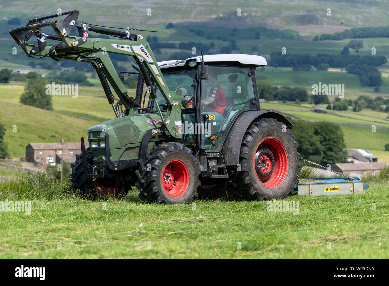 Topping overgrown grass on an upland pasture with a Hurlimann tractor and a Fleming pasture topper. North Yorkshire, UK. Stock Photo