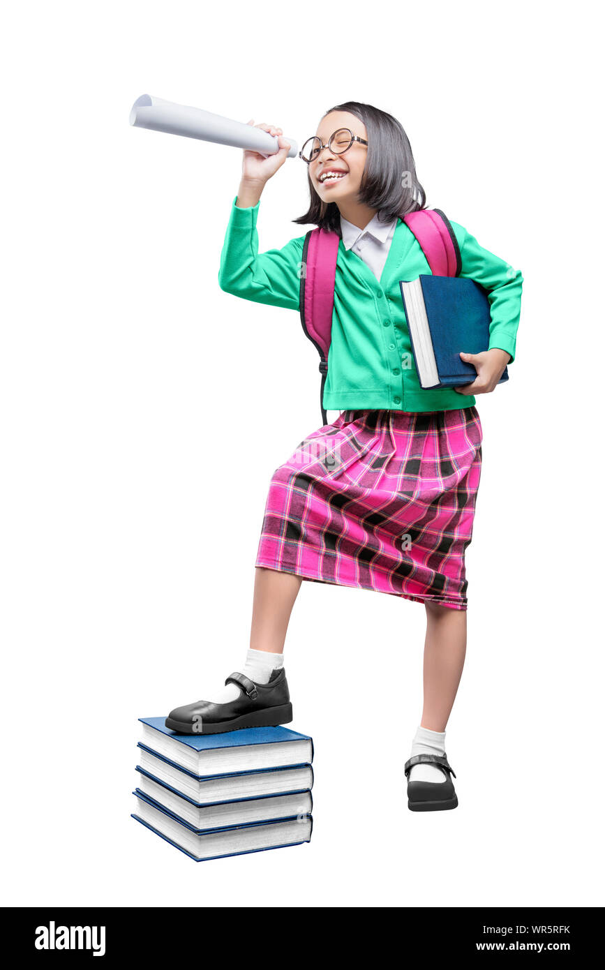 Asian cute girl with a backpack holding the book and paper like a telescope standing isolated over white background Stock Photo