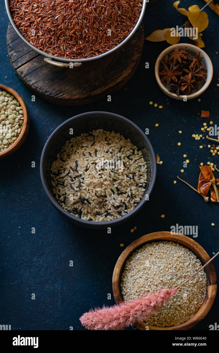 Various types of rice and grains with spices on blue background. Brown ...
