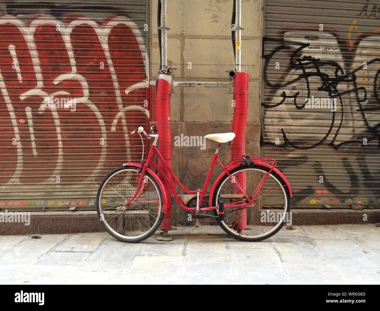 Red Bicycle Parked Against Shopfronts Stock Photo