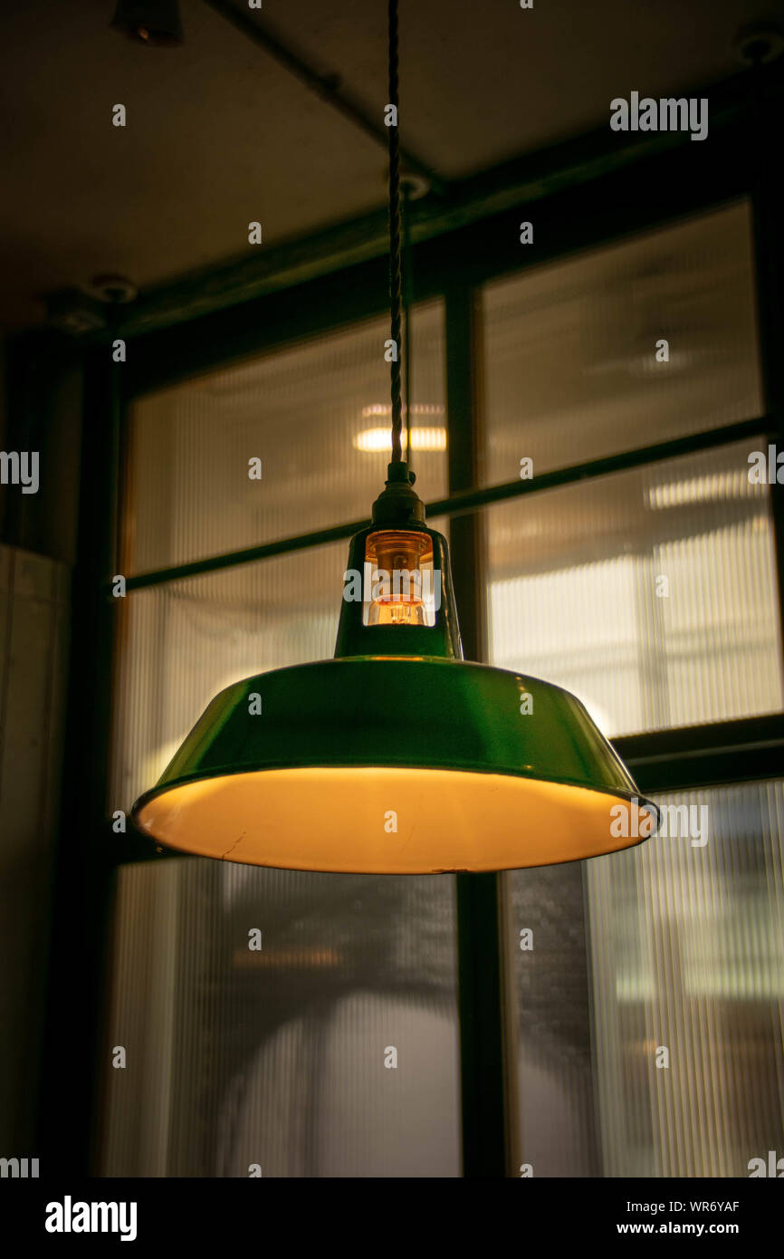 A green industrial style pendant light handing in a warehouse/industrial building Stock Photo