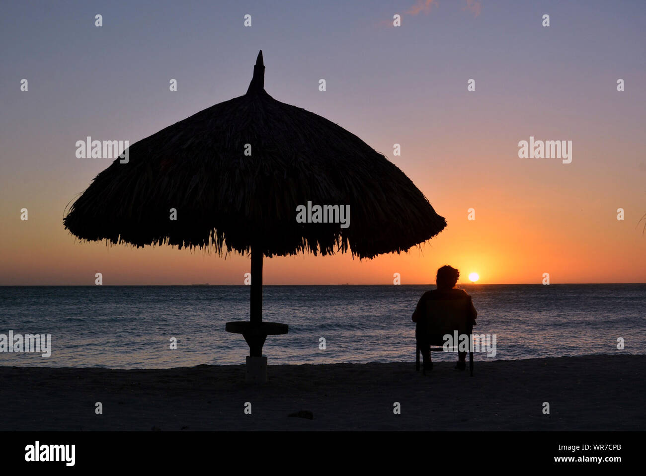 Silhouette Of Man Sitting On Chair At Beach Against Sky During Sunset Stock Photo Alamy