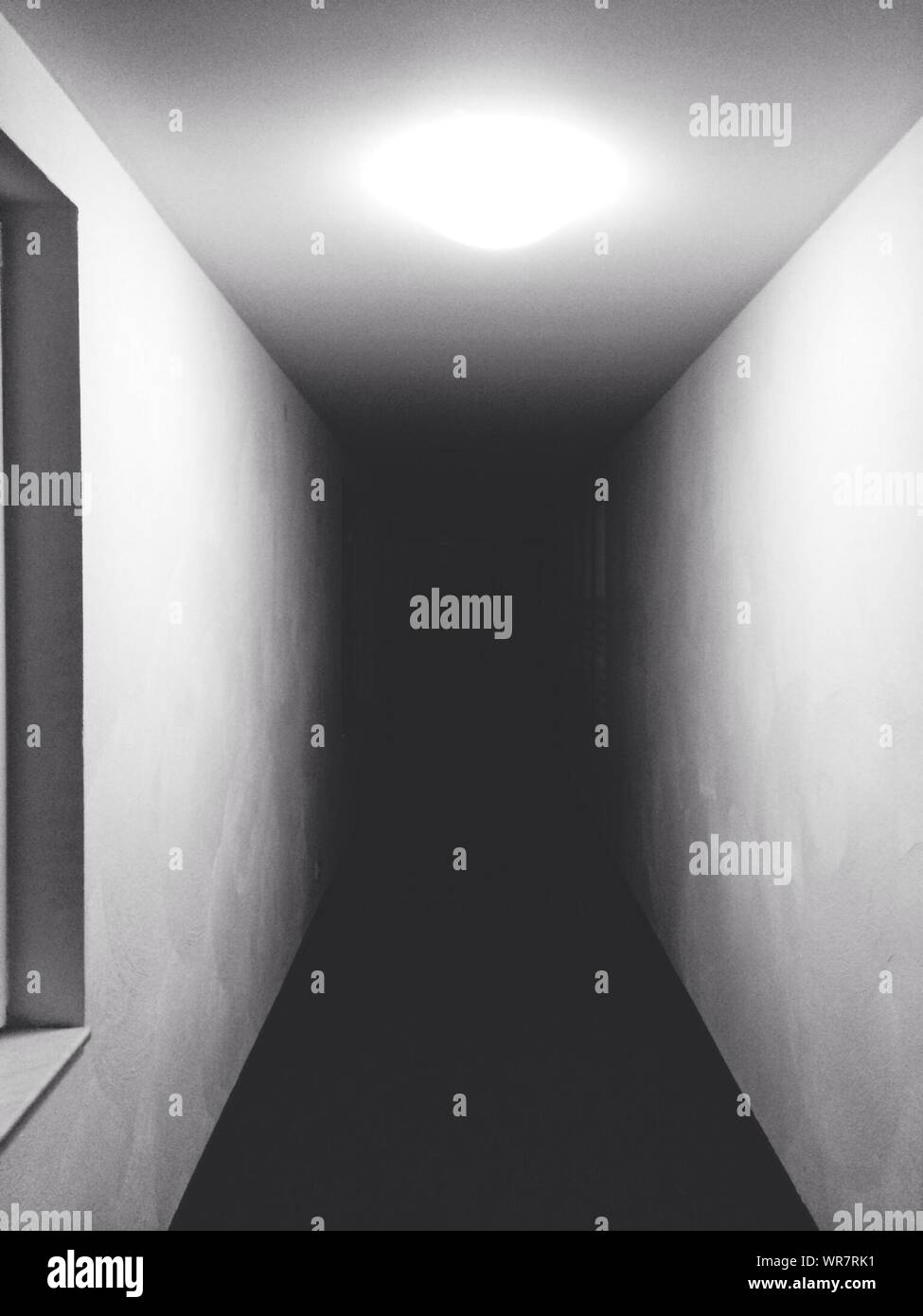 Dark Corridor With White Walls And Ceiling Light Stock Photo