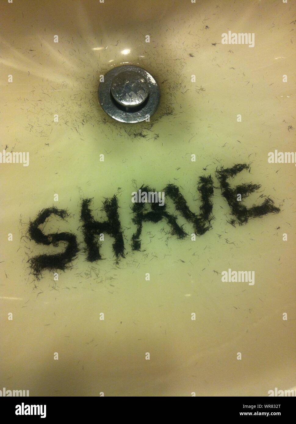 High Angle View Of Shave Text Made By Hair In Bathroom Sink Stock Photo