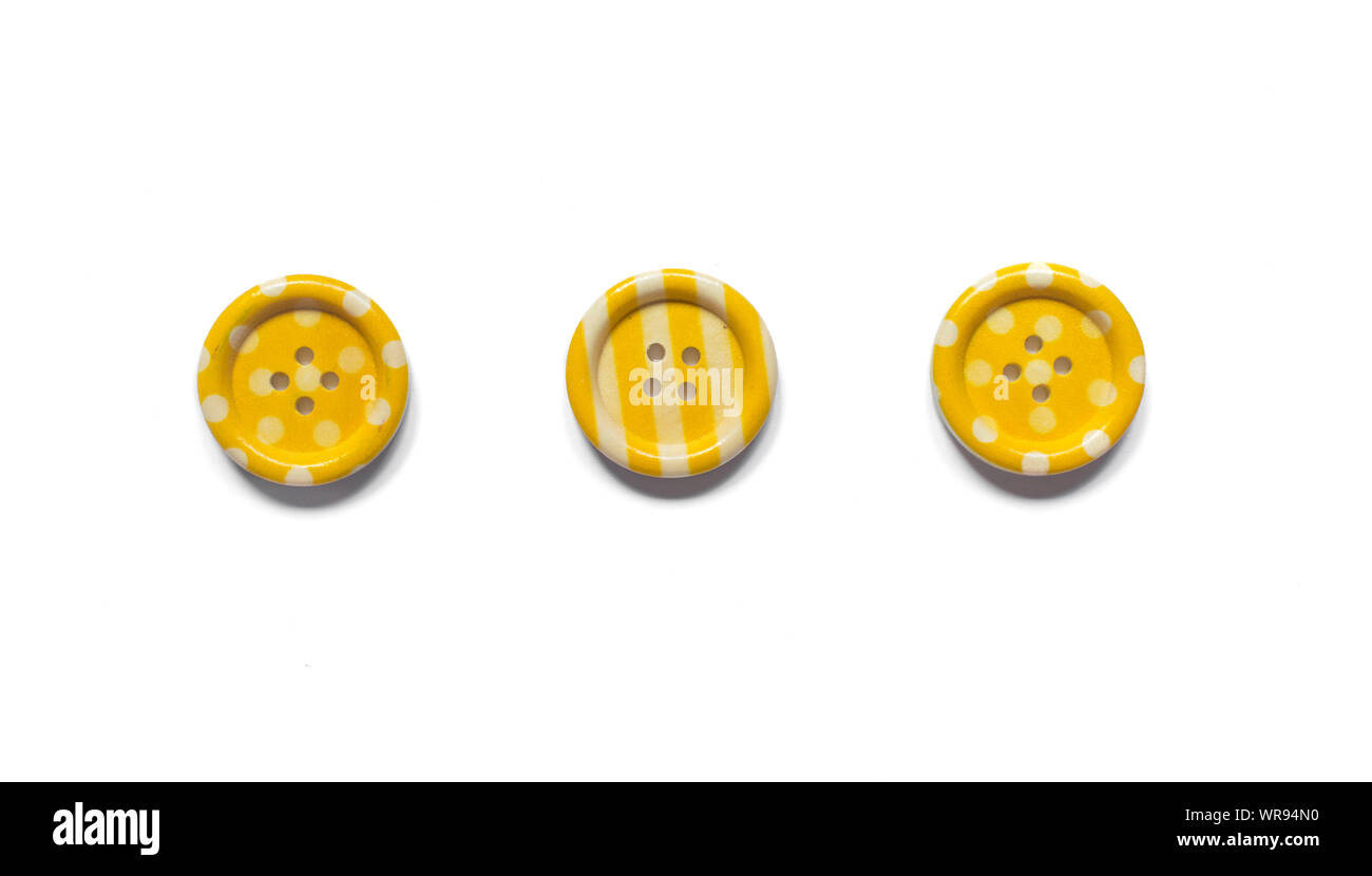 Three Various yellow sewing buttons isolated on background. Stock Photo