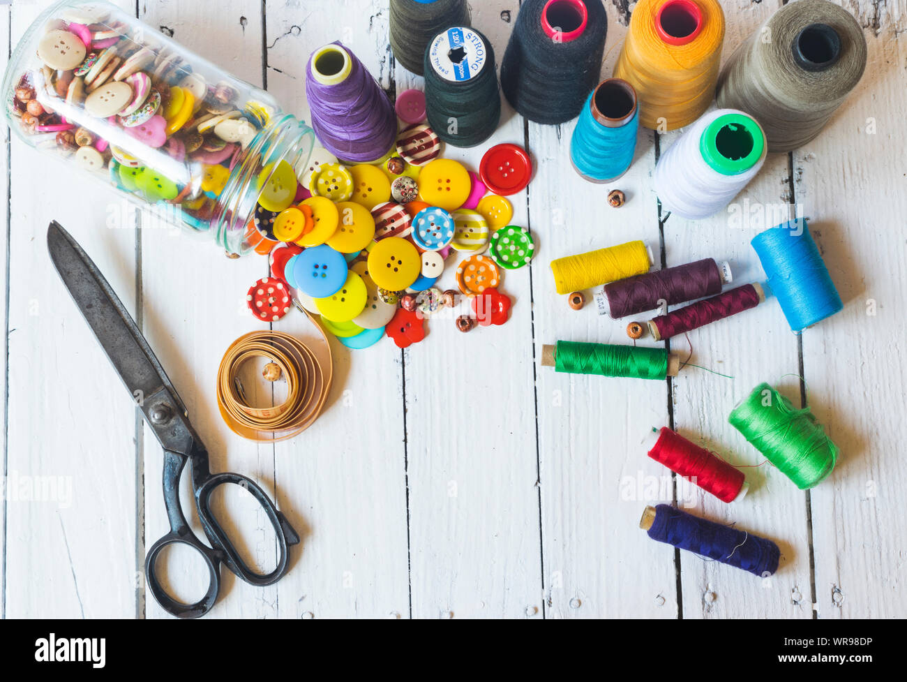 Sewing material (sewing buttons ,sccissors , threads) on old white table. High angle view Stock Photo