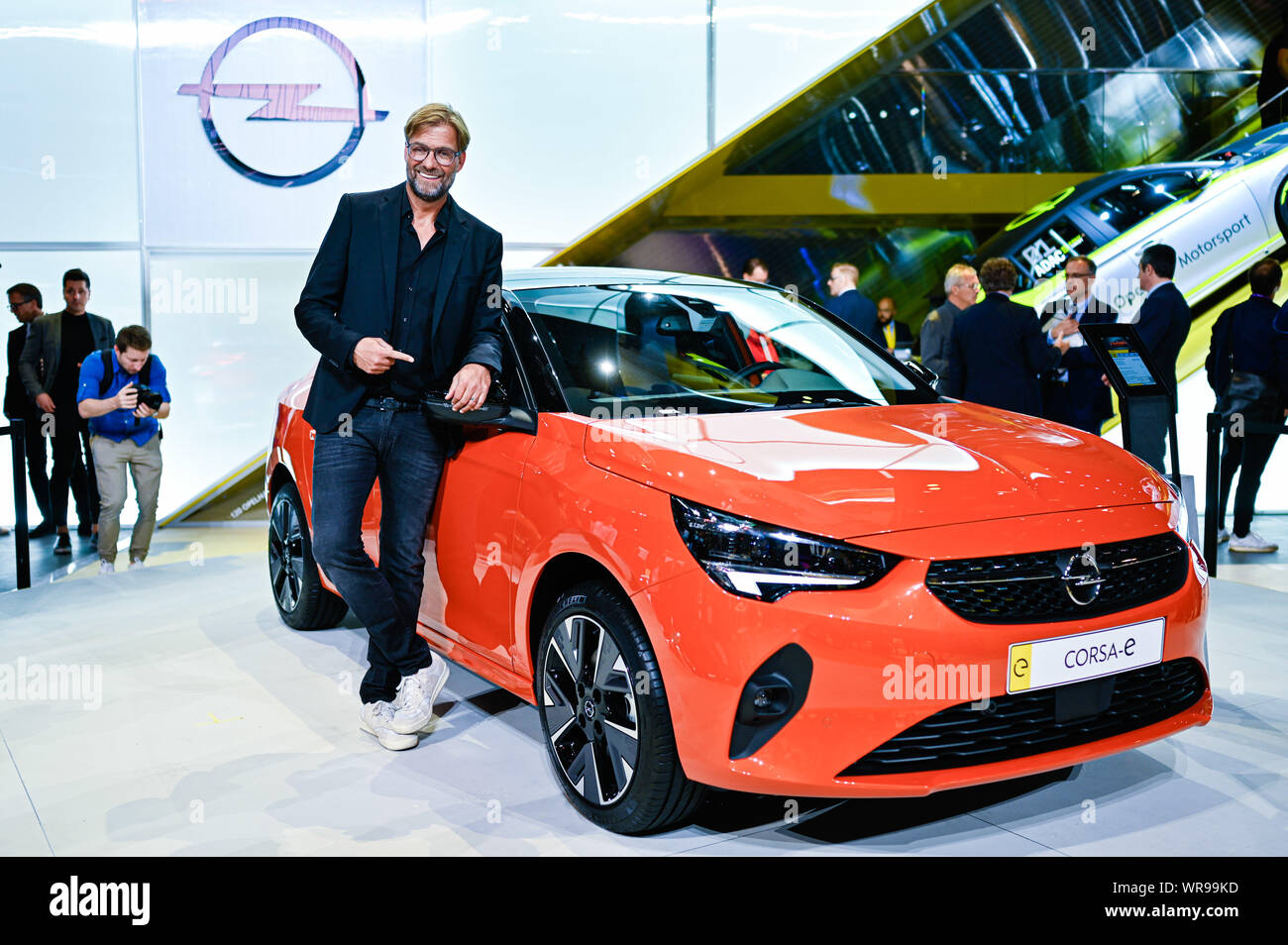 10 September 2019, Hessen, Frankfurt/Main: Jürgen Klopp, coach of the  English football club FC Liverpool, points to an Opel Corsa-E at the IAA at  the stand of the car manufacturer Opel. Photo: