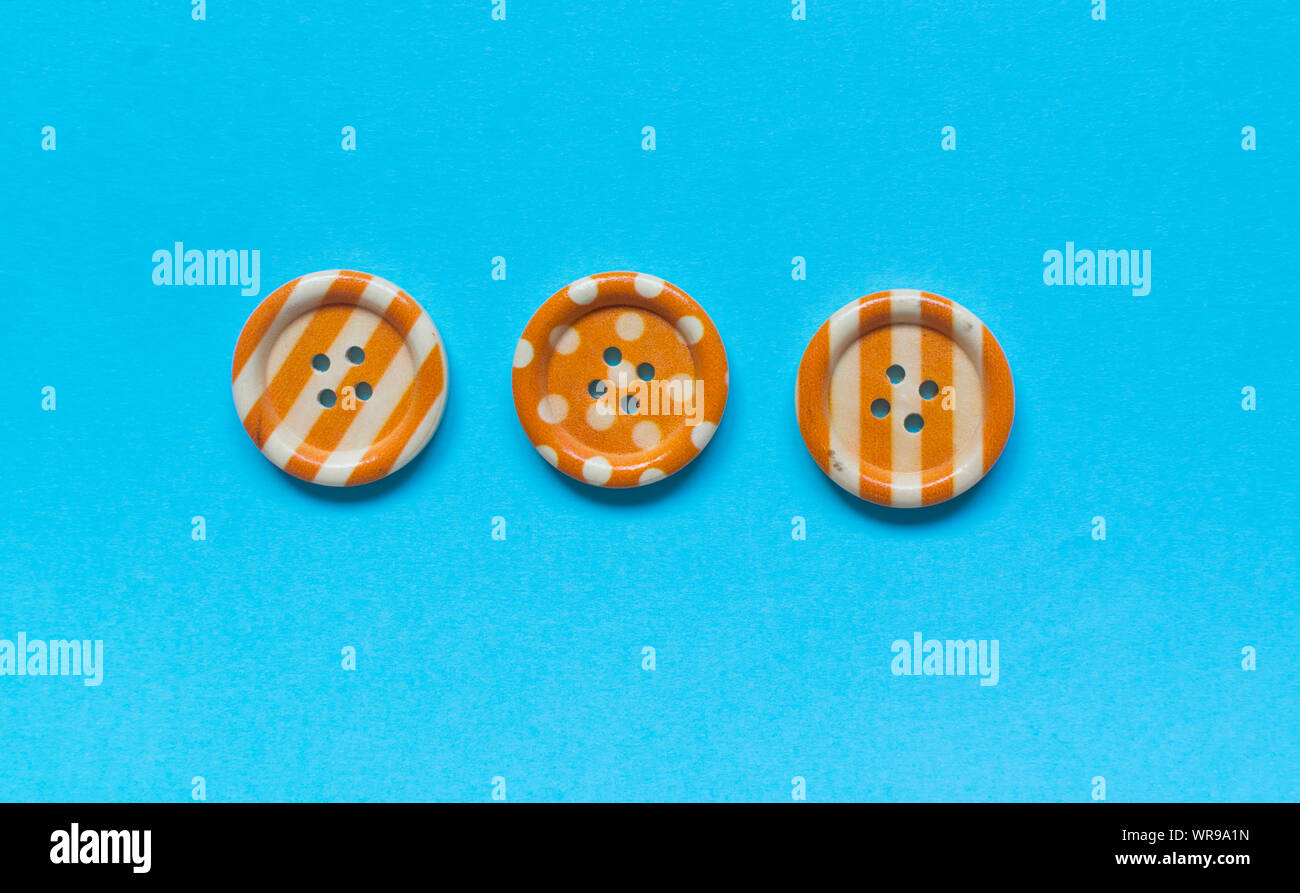 Three Various orange sewing buttons on blue background. Stock Photo