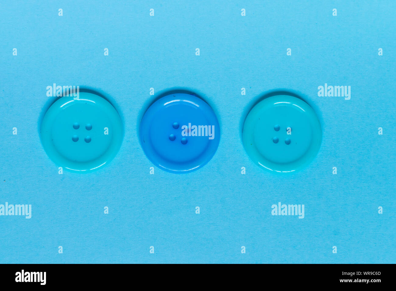 Three Various blue sewing buttons on blue background. Stock Photo