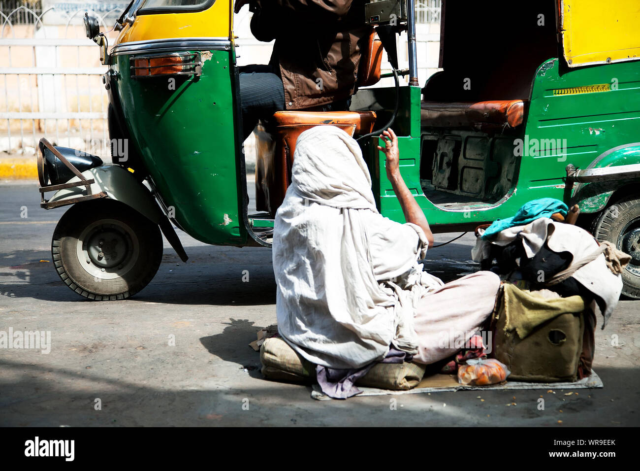 Beggar Begging In Front Of Auto Rickshaw On Street Stock Photo
