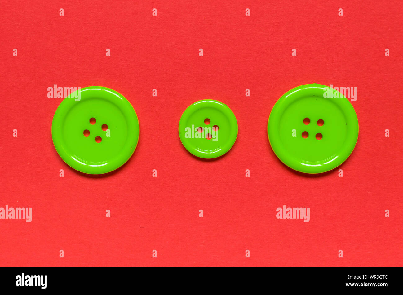 Three Various green sewing buttons  on red background. Stock Photo