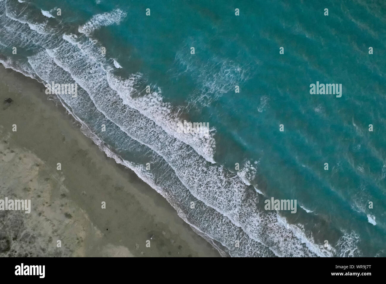 White foamy sea waves splash to sandy beach in the evening. Evening ...