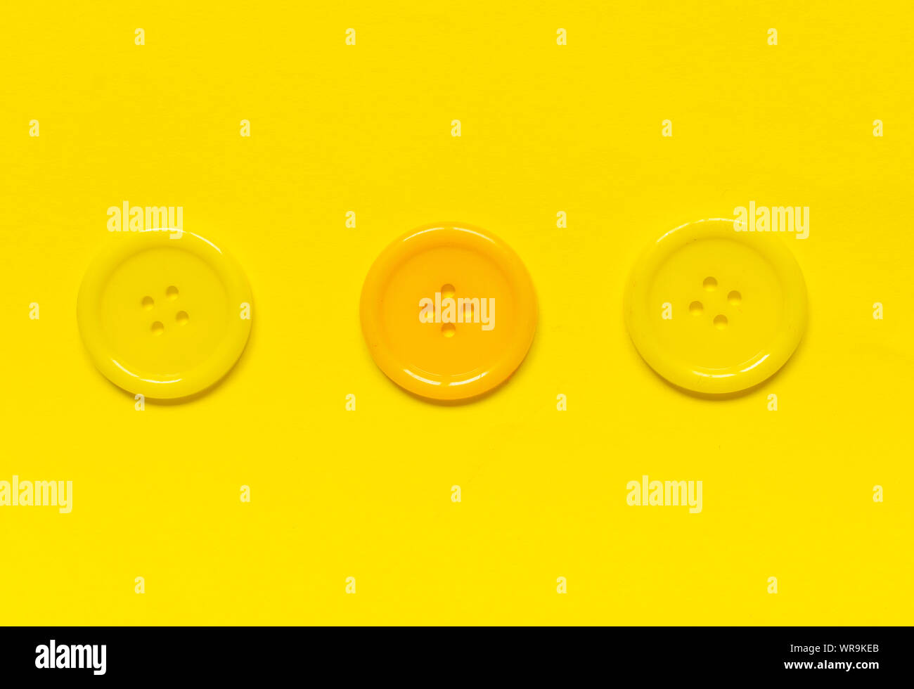 Three Various yellow sewing buttons  on yellow background. Stock Photo