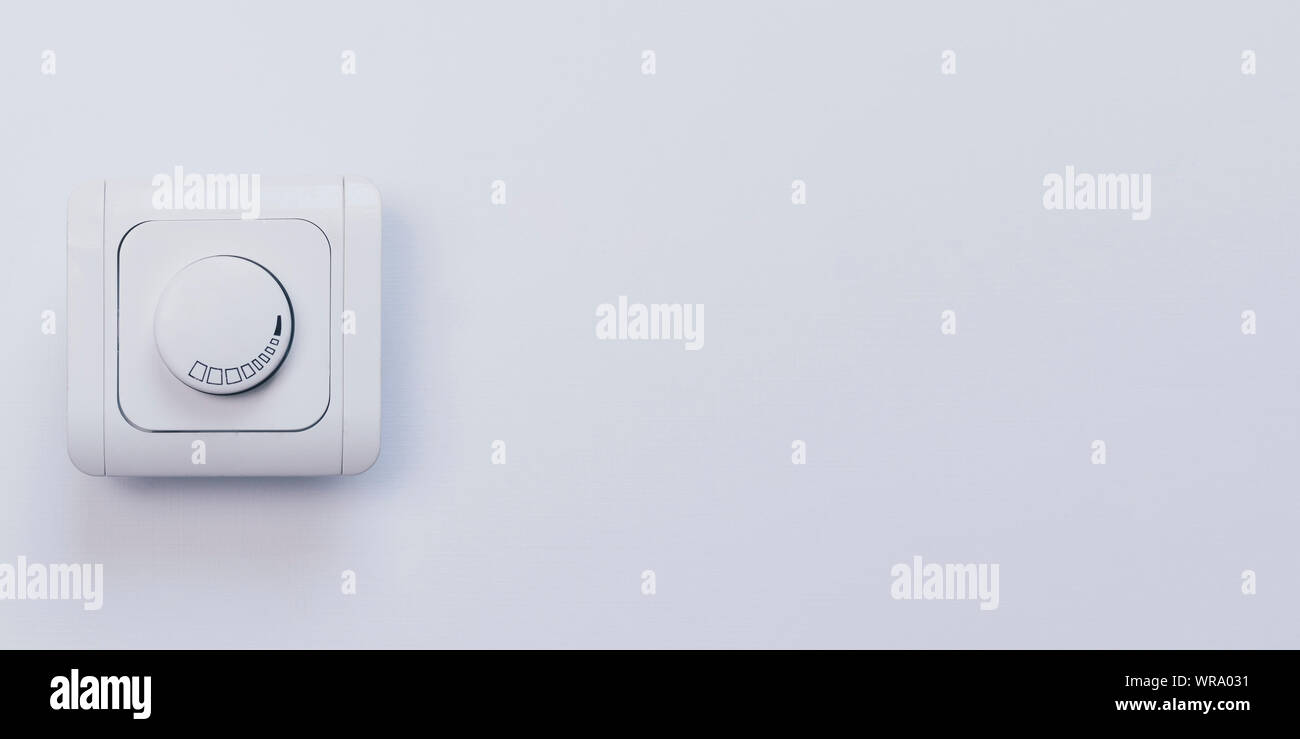 Dimmer Light Switch. Electrician switch. White rolling electricity switch on a bright wall Stock Photo
