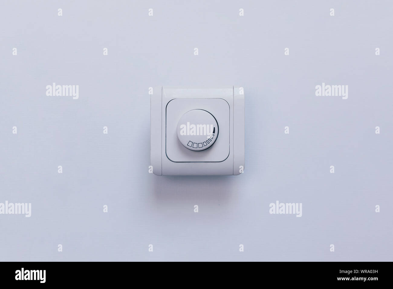 Dimmer Light Switch. Electrician switch. White rolling electricity switch on a bright wall Stock Photo