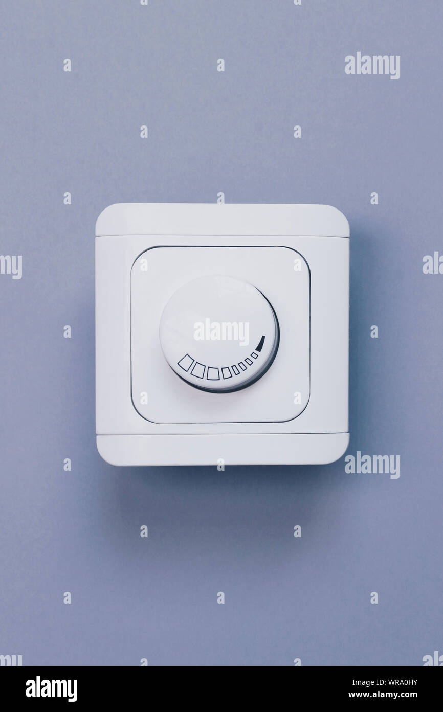 Dimmer Light Switch. Electrician switch. White rolling electricity switch on a bright wall Stock Photo