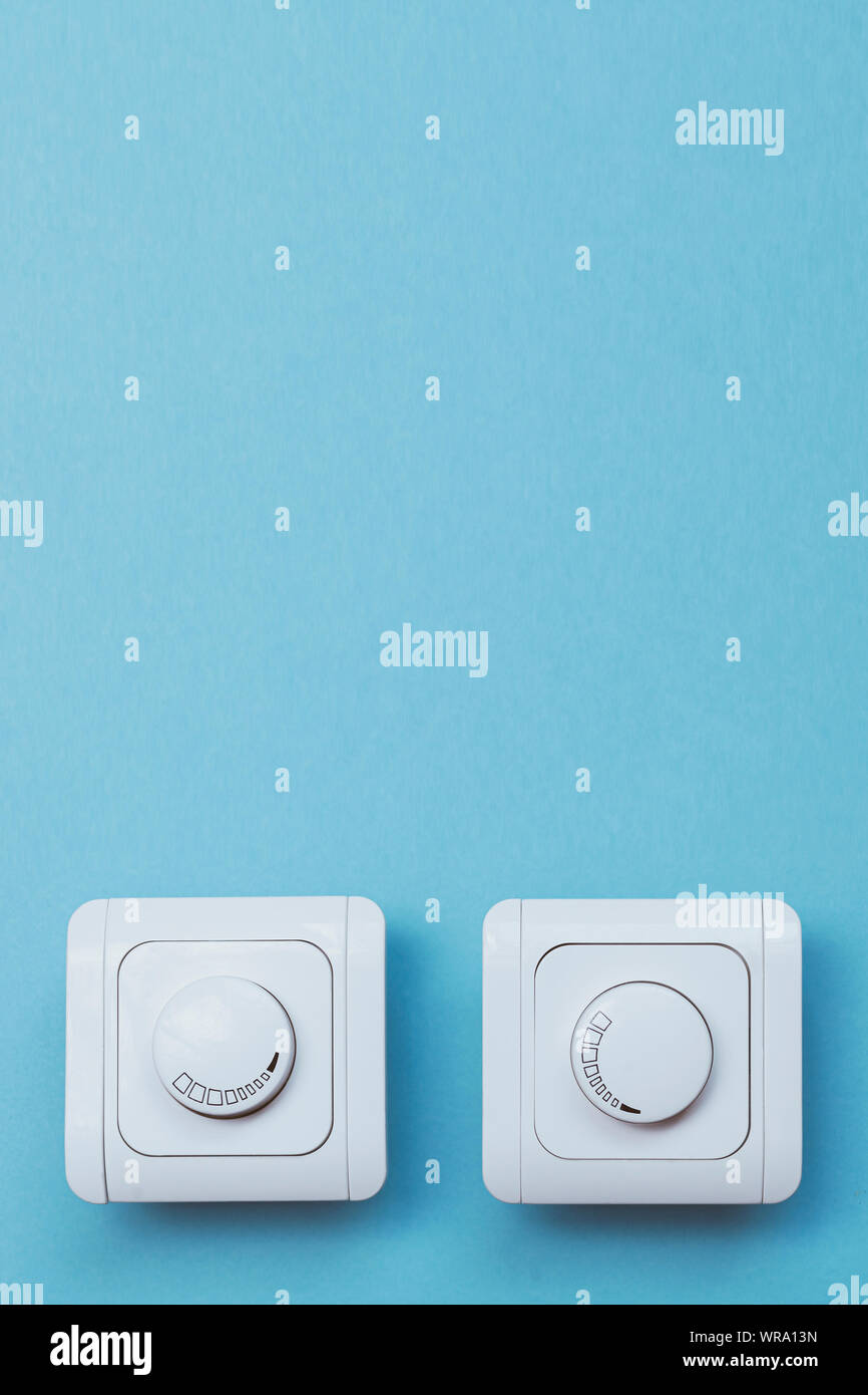 Dimmer Light Switch. Electrician switch. White rolling electricity switch on a bright wall Stock Photo
