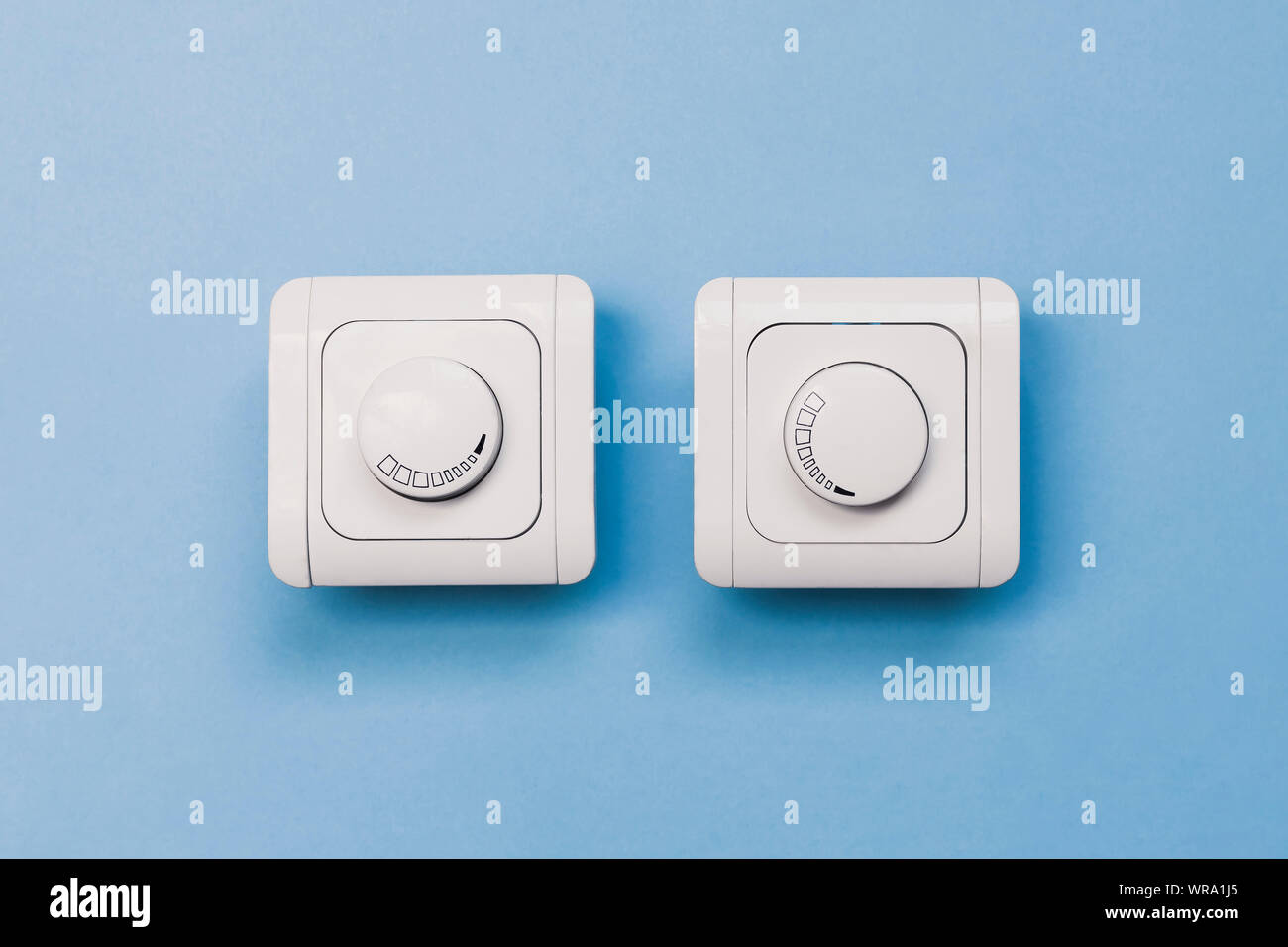 Dimmer Light Switch. Electrician switch. White rolling electricity switch on a bright wall Stock Photo