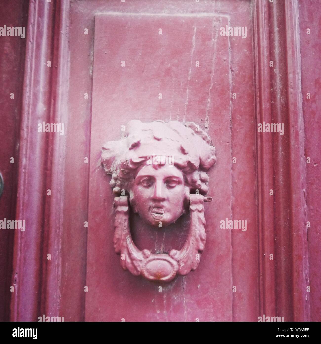 Close-up Of Knocker With Female Carving On Pink Door Stock Photo