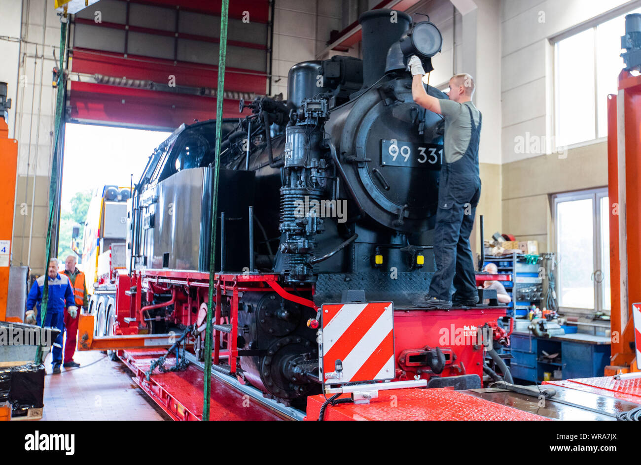 10 September 2019, Mecklenburg-Western Pomerania, Bad Doberan: A historic steam locomotive of the small Milli railway is loaded onto a low-loader and transported to the North Sea island of Borkum on 11.09.2019. The locomotive will operate between the port and the town between 14 and 22 September. The 'Molli' and the Borkumer Kleinbahn share the rare track gauge of 900 millimetres. From Emden the steam locomotive takes the ferry to Borkum. Photo: Jens Büttner/dpa-Zentralbild/dpa Stock Photo