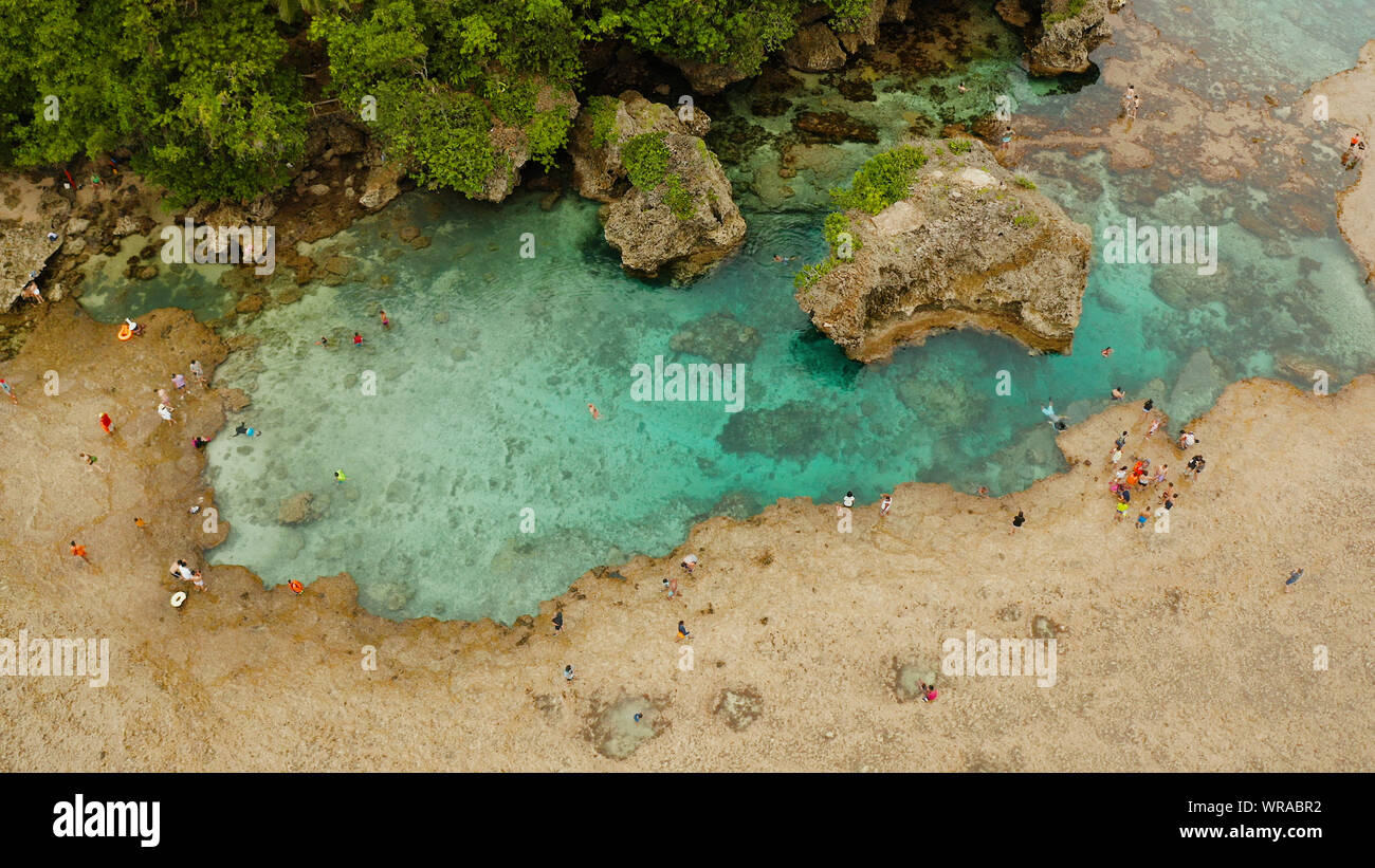 Natural pools on the rocky shore with tourists formed at low tide. Magpupungko natural rock pools. Siargao, Philippines. Stock Photo