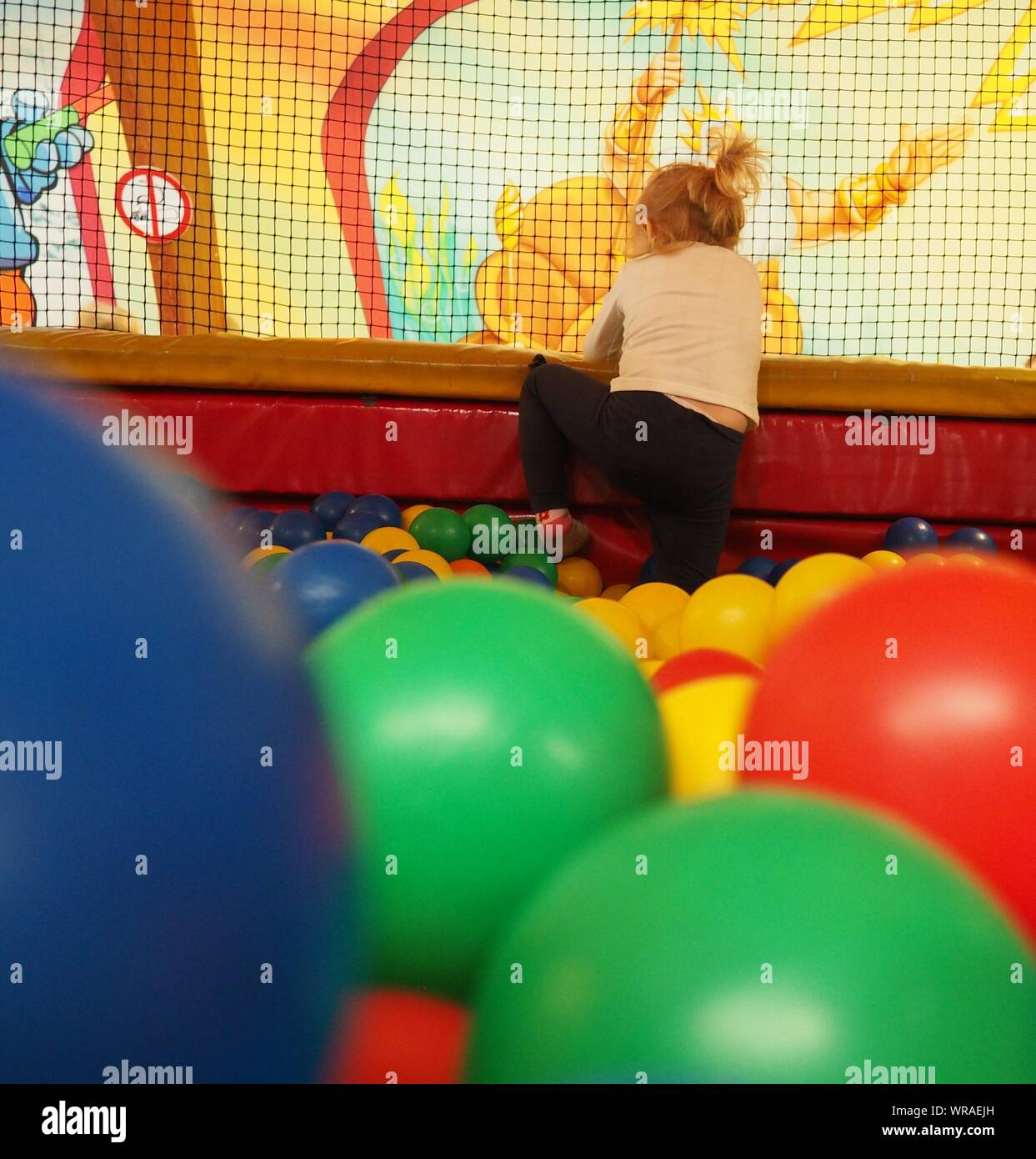 Little Girl climbing out of ball pool Stock Photo Alamy