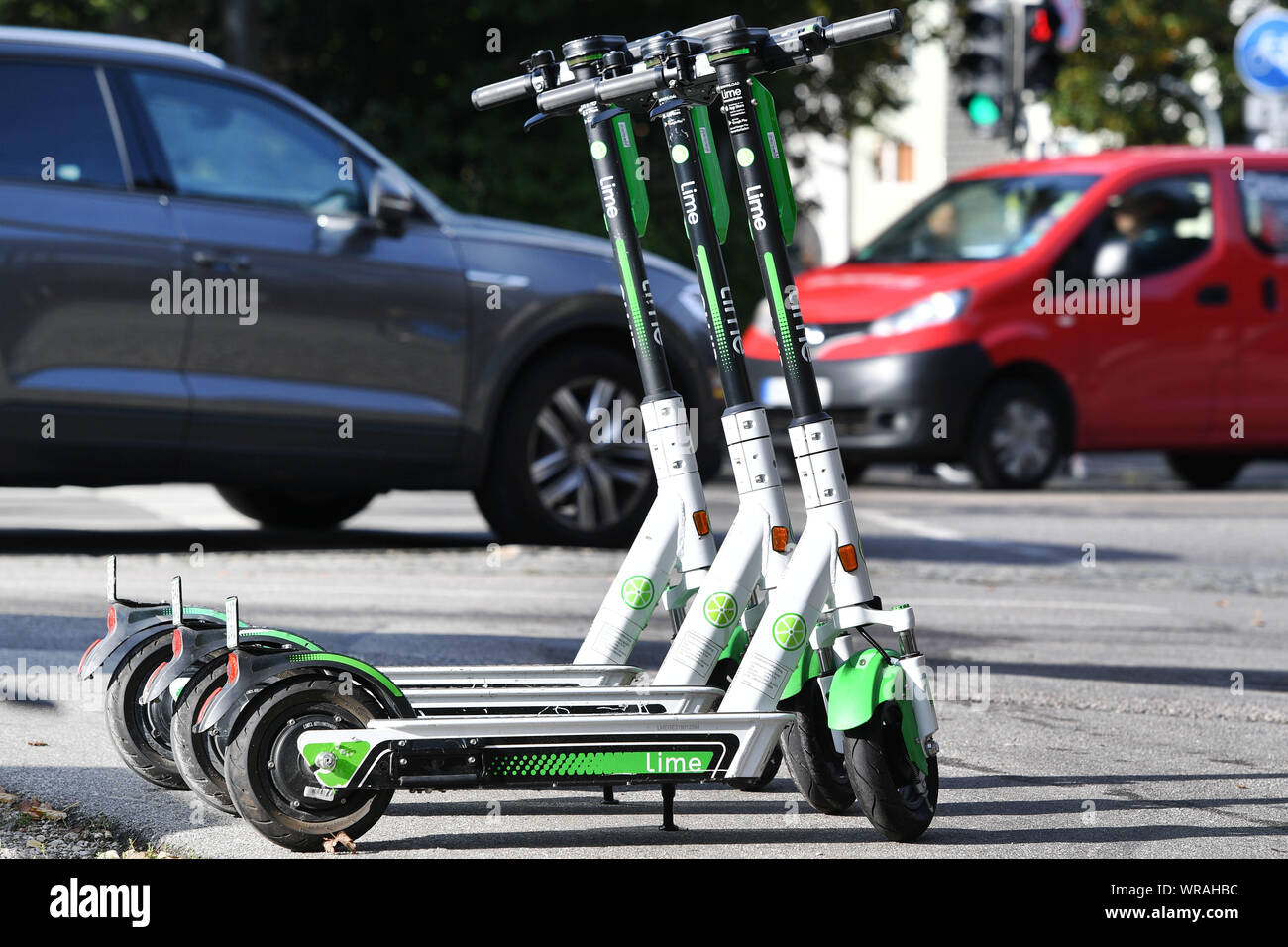 Munich, Deutschland. 10th Sep, 2019. Three e-scooters are arranged side by  side - in the background cars drive. LimeBike, Lime Bike US e-scooter  rental company. E-scooter, e-scooter in the city center of