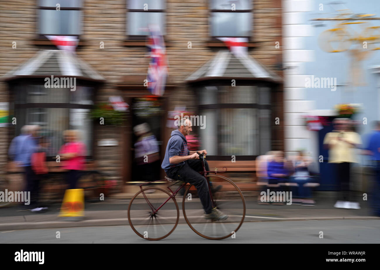 A spectator riding an old fashioned bike in Brough, Cumbria, during stage four of the OVO Energy Tour of Britain from Gateshead to Kendal. Stock Photo