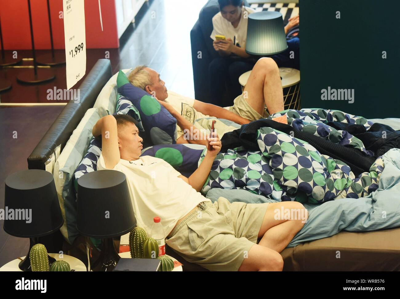 Local Chinese residents nap or rest on the bed or in the sofa at an air-conditioned IKEA furnishing store to escape the heatwave on a scorcher in Hang Stock Photo