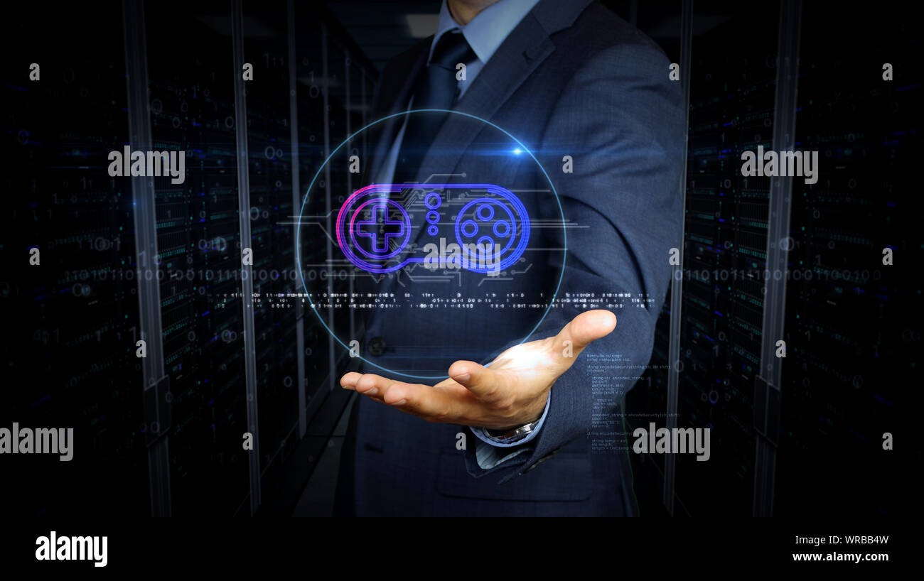 A businessman in a suit touch screen with game pad symbol hologram. Man using hand on virtual display interface. Gaming, 5G, play and online game futu Stock Photo