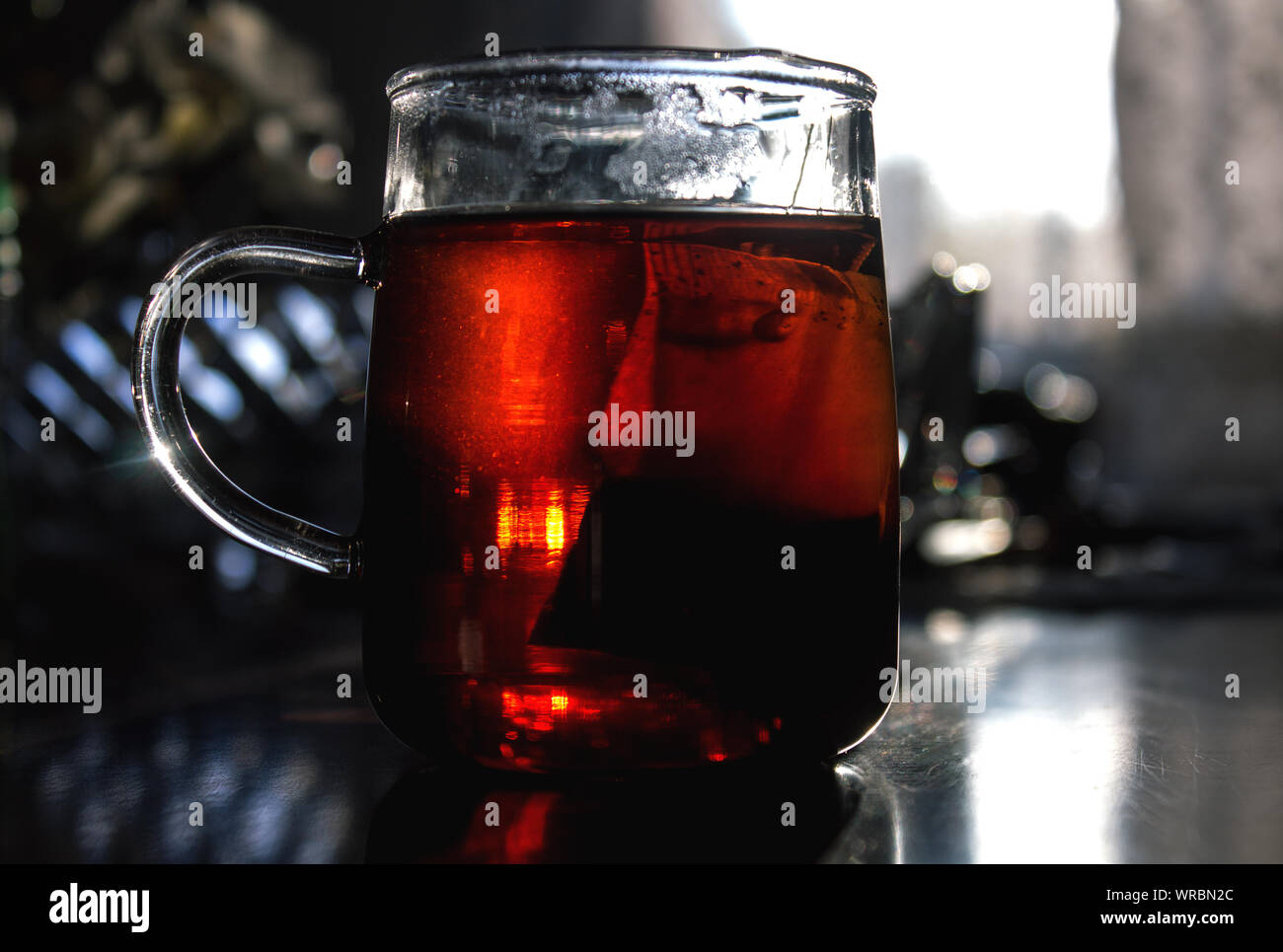 A teabag rests in a glass tea cup on wooden table in the morning,  in low angle close up  selective focus image with copy space. Stock Photo