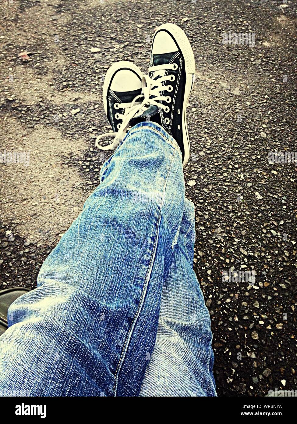 Low Section Of Man Wearing Denim Jeans And Canvas Shoe Stock Photo - Alamy