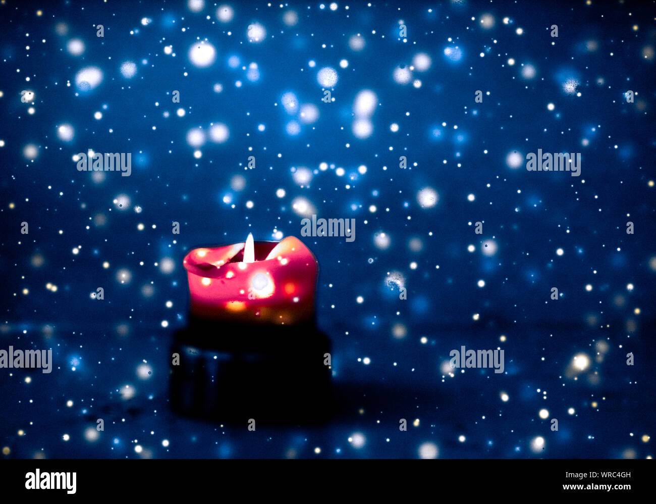 Happy holidays, greeting card and winter season concept - Red holiday candle on blue sparkling ...