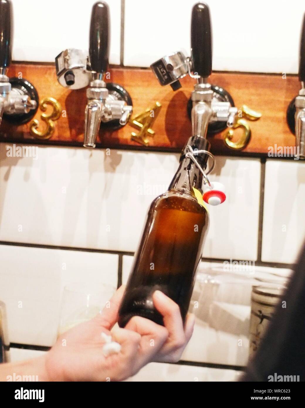 Cropped Hand Filling Bottle From Beer Tap In Restaurant Stock Photo