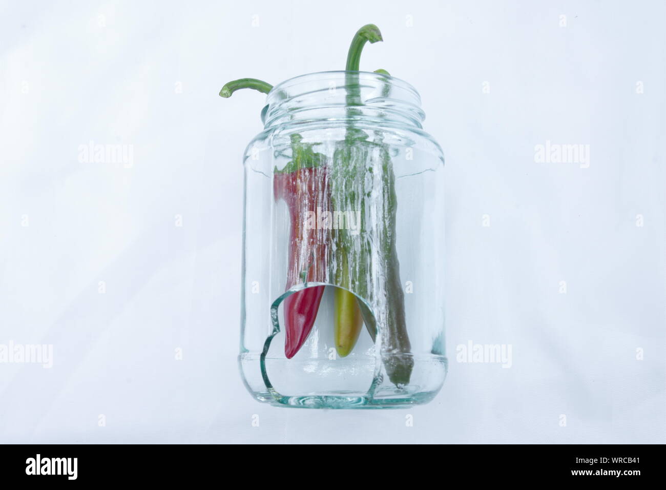 Three hot chili peppers in a broken jar Stock Photo Alamy