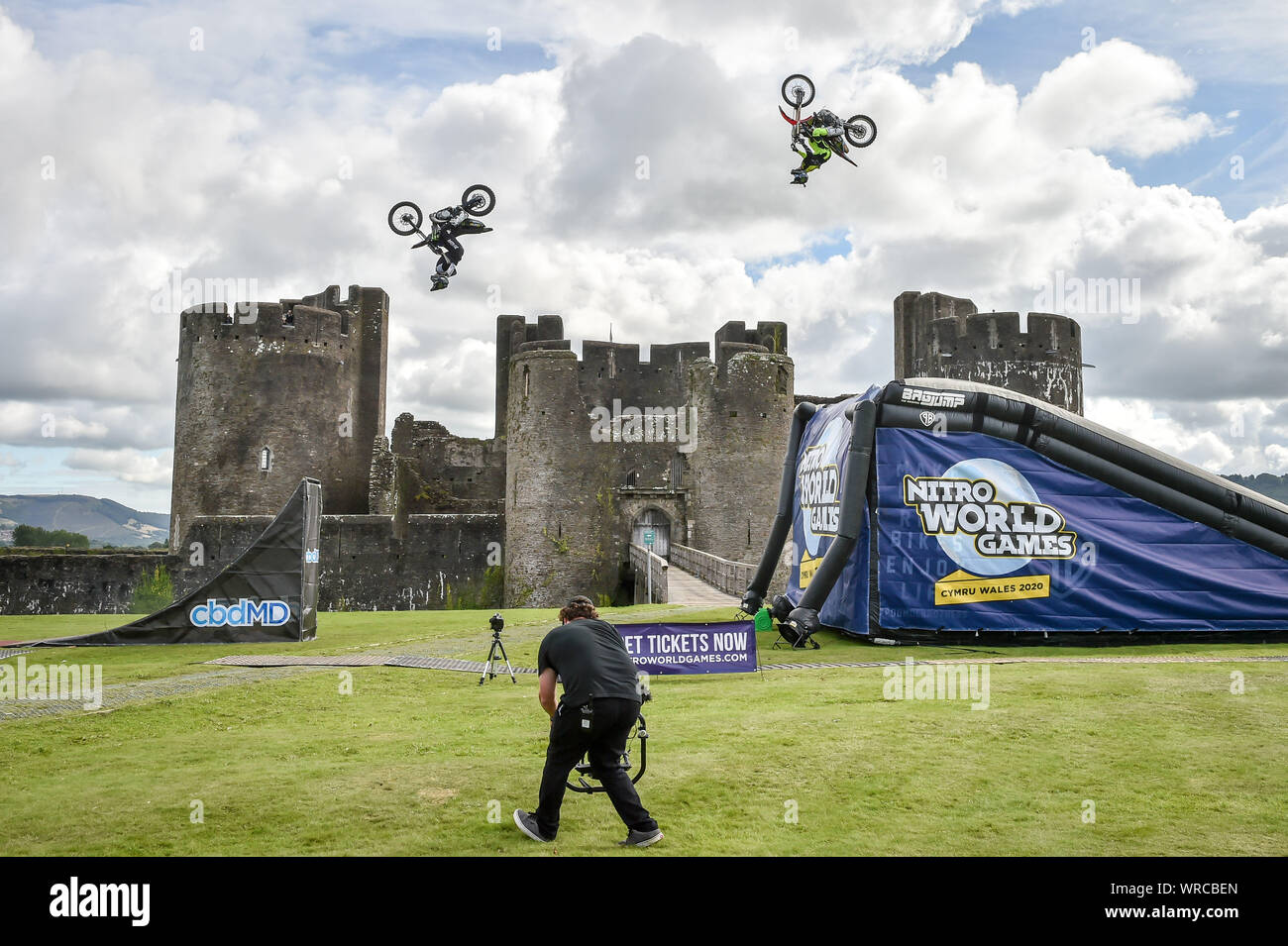 World Nitro Games athletes jump over Caerphilly Castle, Wales, as they pull off the world's first three-rider double backflip train. Stock Photo